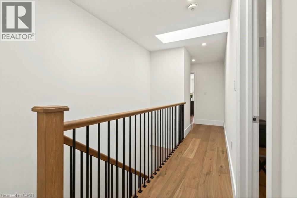 Hallway featuring wood-finish flooring, a contemporary wood and black metal baluster railing, recessed lighting, and a skylight - 128 Canada Street, Hamilton, ON - Indoor Photo Showing Other Room