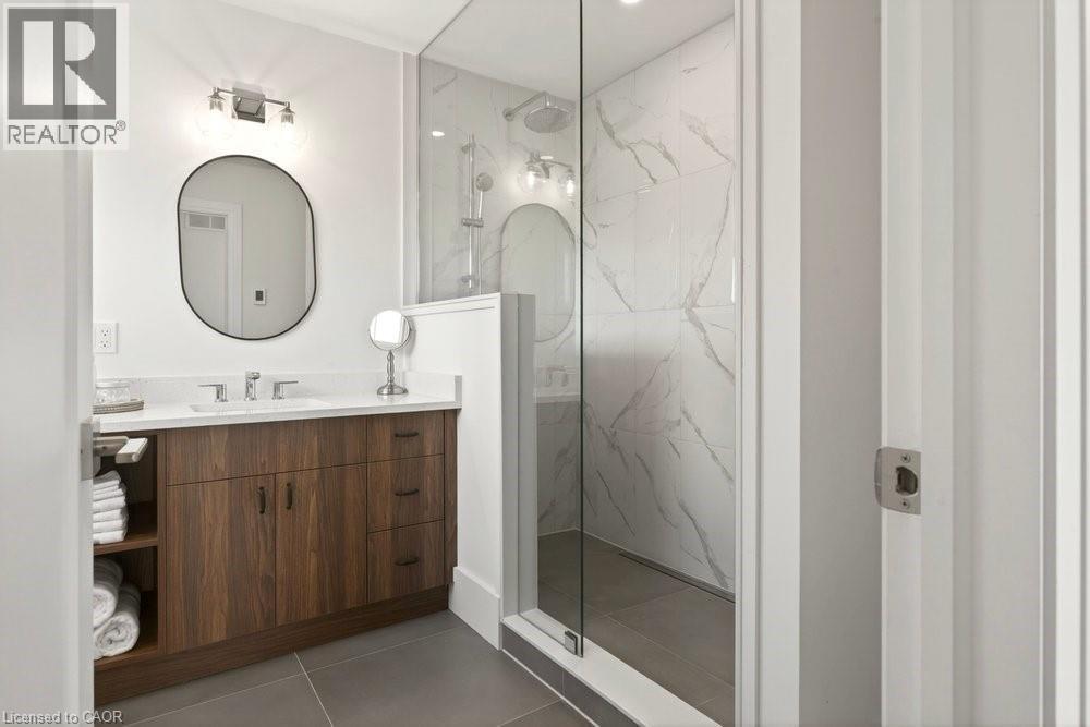 Bathroom featuring a glass-enclosed shower with white marble-style tiled walls and a rain showerhead - 128 Canada Street, Hamilton, ON - Indoor Photo Showing Bathroom