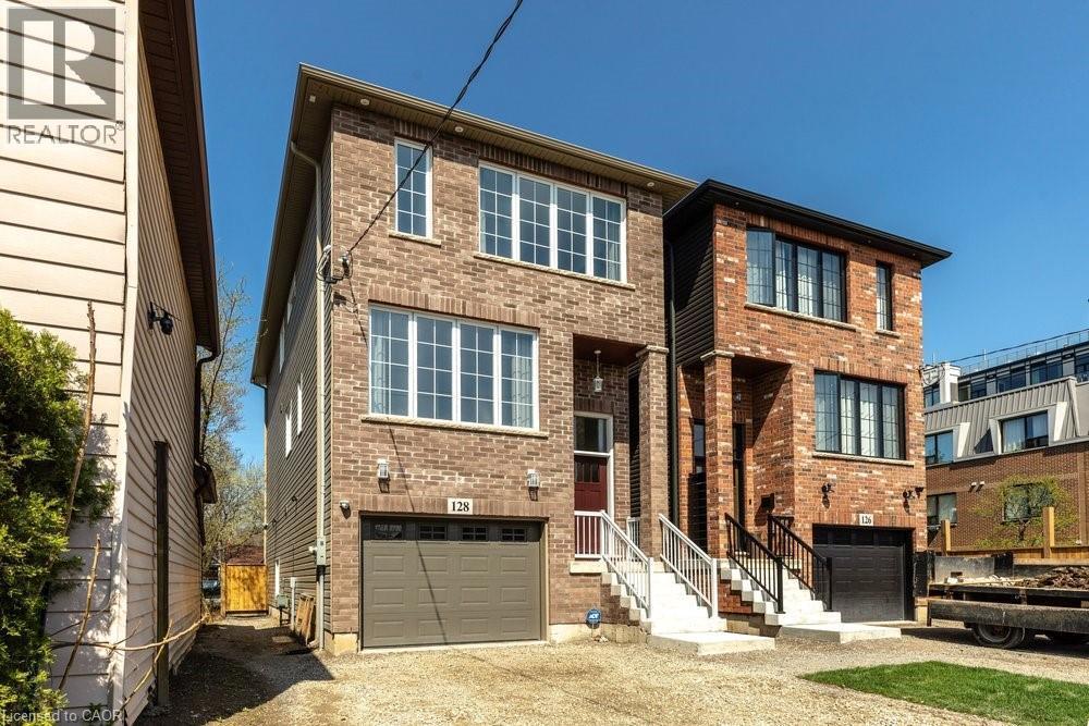 Brick exterior with contrasting trim, multiple windows across two levels, an integrated garage, and a covered entryway - 128 Canada Street, Hamilton, ON - Outdoor