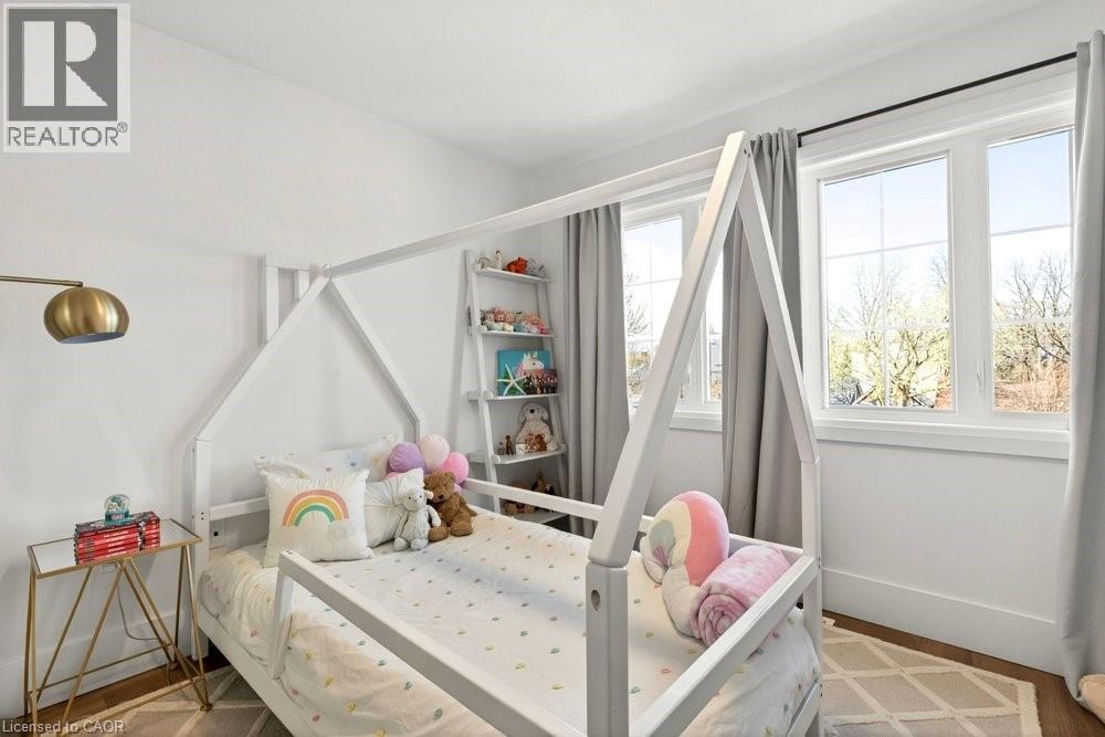 Bright room featuring two large windows, white walls, and wood-finish flooring - 128 Canada Street, Hamilton, ON - Indoor Photo Showing Bedroom