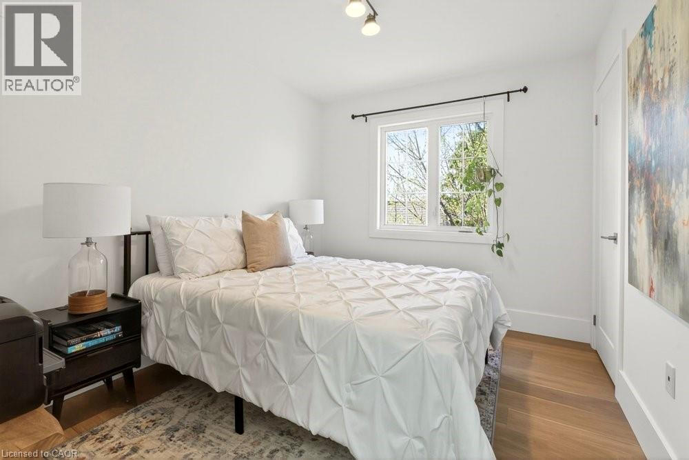 Bright room featuring light wood-finish flooring, white walls, and a white-trimmed window - 128 Canada Street, Hamilton, ON - Indoor Photo Showing Bedroom
