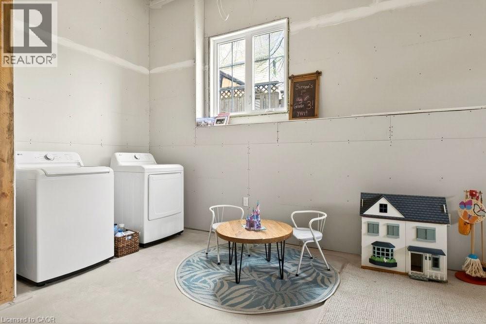 Dedicated utility space featuring a washer and dryer set, drywall-finished walls, and a window providing natural light - 128 Canada Street, Hamilton, ON - Indoor Photo Showing Laundry Room