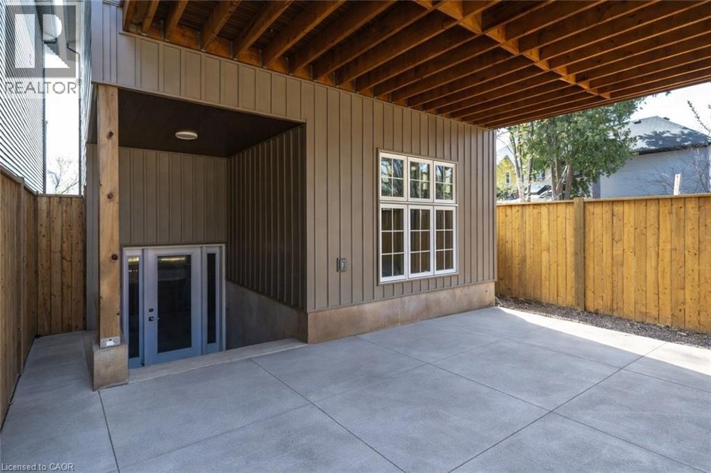Covered concrete patio space featuring exposed wood joists and a privacy fence - 128 Canada Street, Hamilton, ON - Outdoor With Deck Patio Veranda With Exterior