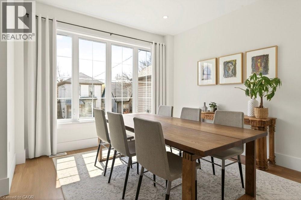 Dining area with expansive multi-pane windows, wood-finish flooring, recessed ceiling lighting, and crisp white walls - 128 Canada Street, Hamilton, ON - Indoor Photo Showing Dining Room