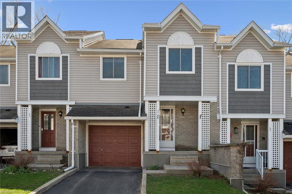 Contemporary townhome exterior featuring light-toned siding with dark grey shingle accents and white trim - 365 Pioneer Drive Unit# 25, Kitchener, ON - Outdoor With Facade
