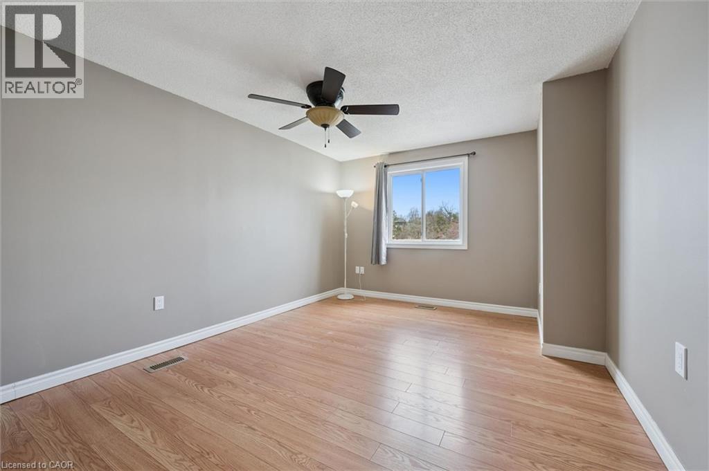 Spacious room featuring wood-finish flooring, a ceiling fan, and a large window with white trim - 365 Pioneer Drive Unit# 25, Kitchener, ON - Indoor Photo Showing Other Room