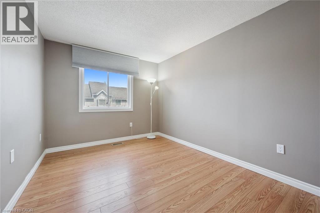 Room featuring wood-finish flooring, a window with a roller blind, and light gray painted walls - 365 Pioneer Drive Unit# 25, Kitchener, ON - Indoor Photo Showing Other Room