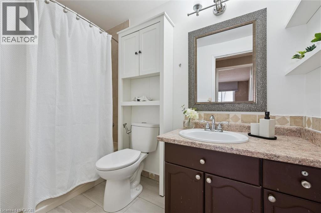 Bathroom featuring a shower with tile surround, toilet, and vanity with an integrated sink - 365 Pioneer Drive Unit# 25, Kitchener, ON - Indoor Photo Showing Bathroom