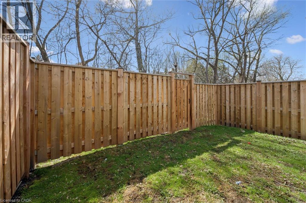 Fenced yard area featuring natural wood fencing and a grassy ground cover - 365 Pioneer Drive Unit# 25, Kitchener, ON - Outdoor