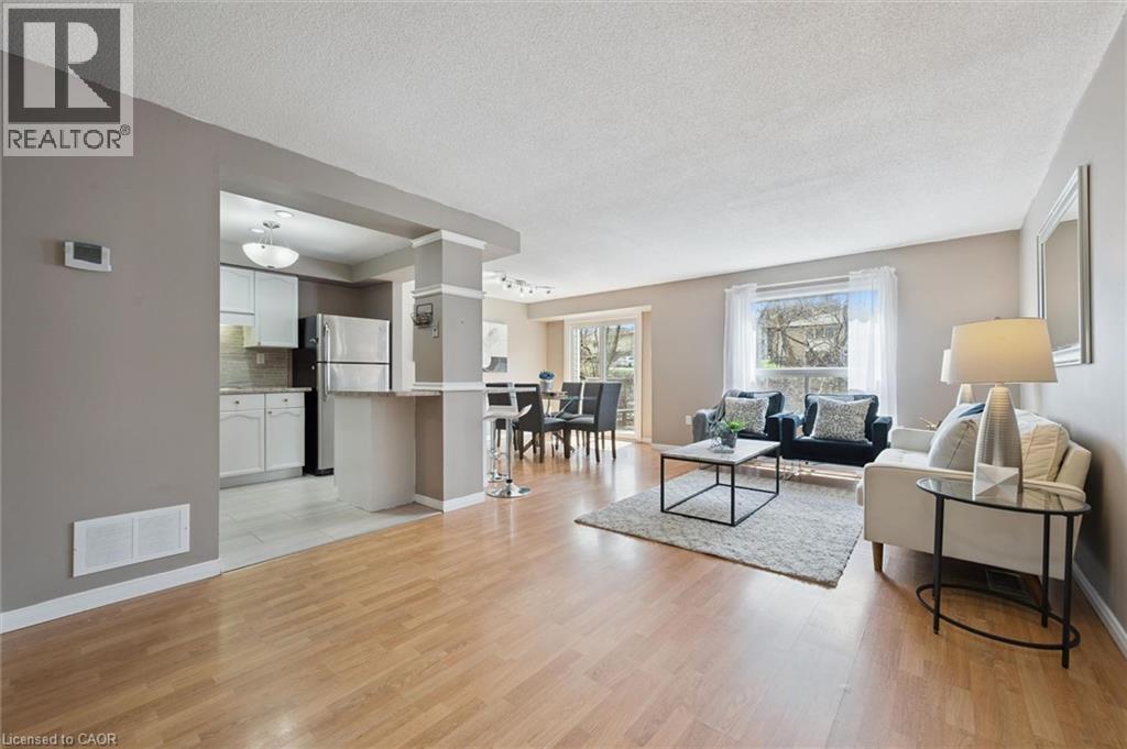 Open-concept living space featuring wood-finish flooring, a kitchen with stainless steel appliances, and a dining area with direct outdoor access - 365 Pioneer Drive Unit# 25, Kitchener, ON - Indoor Photo Showing Living Room