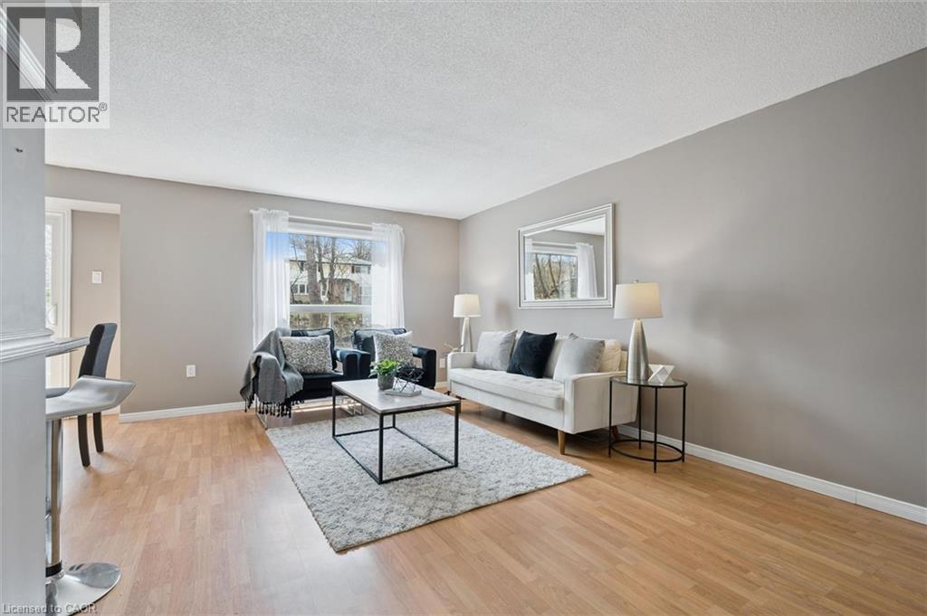 Living area with wood-finish flooring, neutral wall paint, and a large window - 365 Pioneer Drive Unit# 25, Kitchener, ON - Indoor Photo Showing Living Room