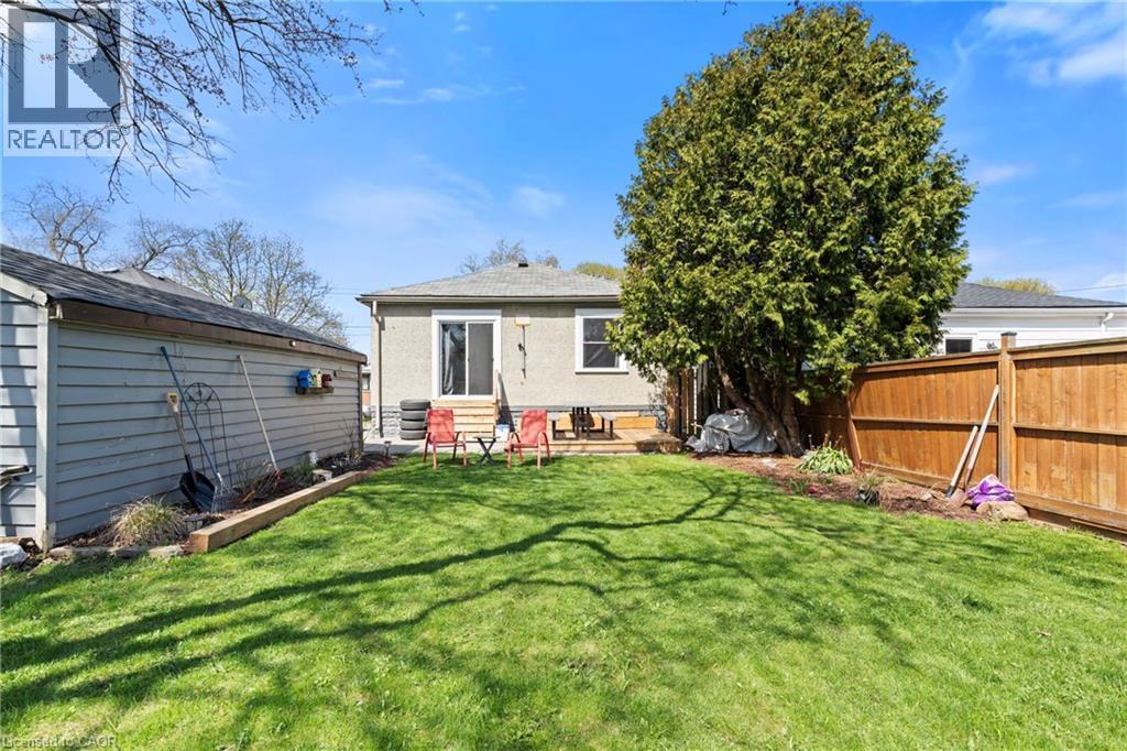 Expansive backyard with manicured lawn, mature tree, and wood privacy fence - 25 East 39Th Street, Hamilton, ON - Outdoor