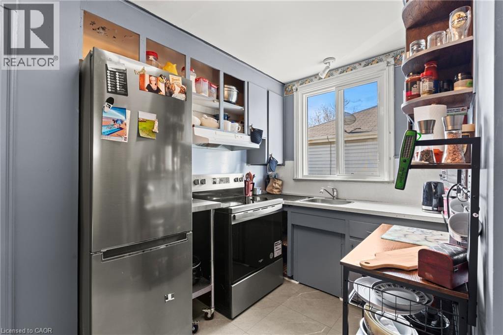 Kitchen featuring a stainless steel refrigerator, white countertops, gray cabinetry, a double-pane window, and tile flooring - 25 East 39Th Street, Hamilton, ON - Indoor Photo Showing Other Room