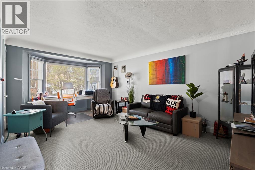 Living area with textured carpeting, a broad bay window, and light gray wall paint - 25 East 39Th Street, Hamilton, ON - Indoor Photo Showing Living Room