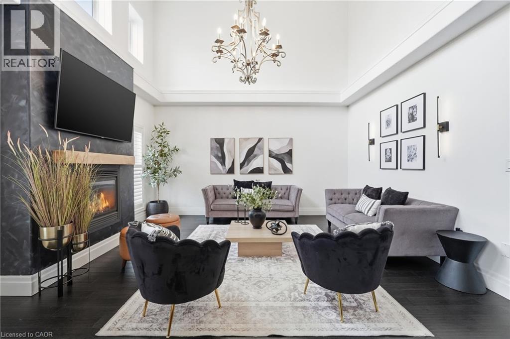 Two-story living area featuring a fireplace with a wood-finish mantel and a dark stone-look surround - 47 Winners Way, Binbrook, ON - Indoor Photo Showing Living Room With Fireplace
