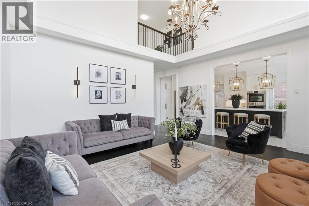 Soaring two-story living area featuring a decorative chandelier, dark wood-finish flooring, and a kitchen pass-through - 47 Winners Way, Binbrook, ON - Indoor Photo Showing Living Room