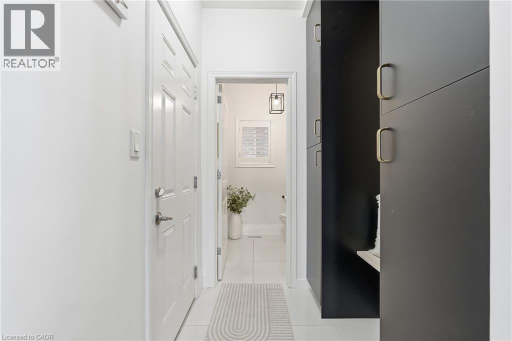 Entryway featuring a white paneled door, built-in dark cabinetry with gold hardware, and tile flooring - 47 Winners Way, Binbrook, ON - Indoor Photo Showing Other Room