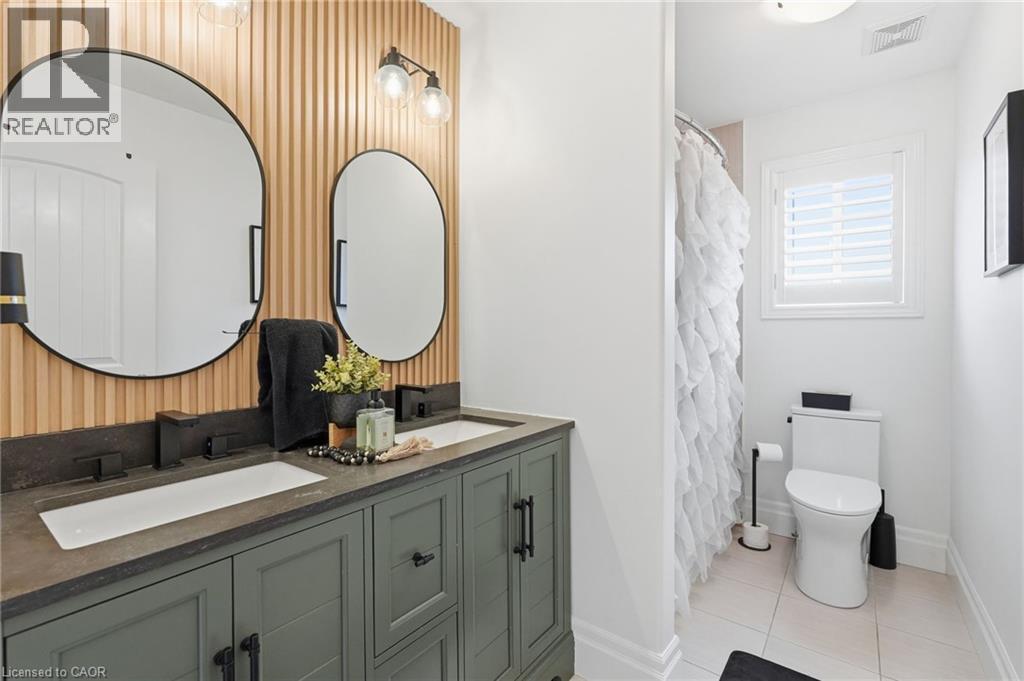 Dual vanity with a stone-finish countertop, undermount sinks, and matte black fixtures - 47 Winners Way, Binbrook, ON - Indoor Photo Showing Bathroom