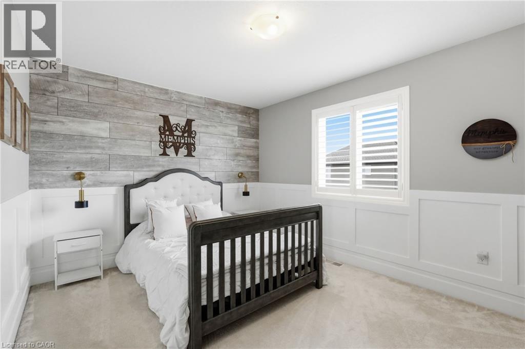 Bedroom featuring a whitewashed wood-finish accent wall, white wainscoting, and a window with plantation shutters - 47 Winners Way, Binbrook, ON - Indoor Photo Showing Bedroom