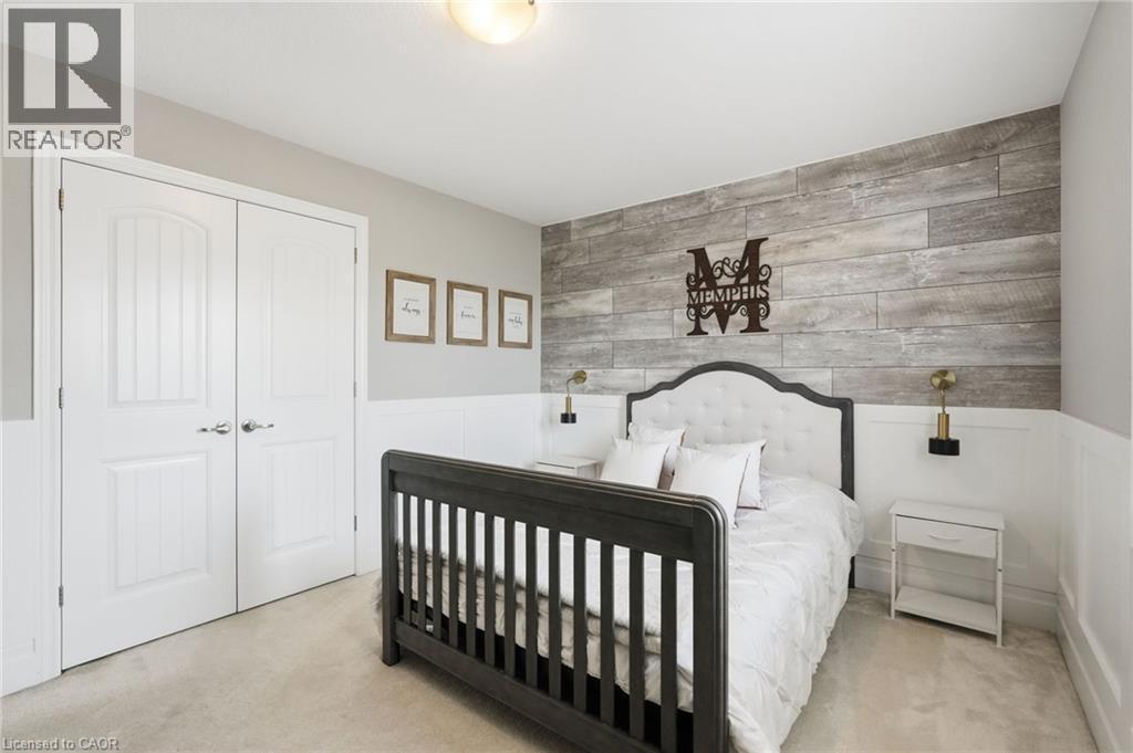 Interior space featuring a wood-finish accent wall, wainscoting, and carpet flooring - 47 Winners Way, Binbrook, ON - Indoor Photo Showing Bedroom