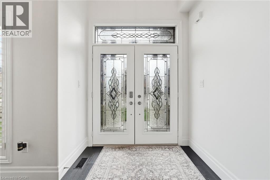 Double entry doors with decorative glass panels and an arched transom window - 47 Winners Way, Binbrook, ON - Indoor Photo Showing Other Room