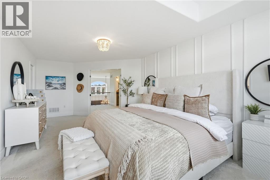 Carpeted bedroom featuring a white upholstered bed frame, a feature wall with vertical paneling, and a chandelier-style ceiling light - 47 Winners Way, Binbrook, ON - Indoor Photo Showing Bedroom