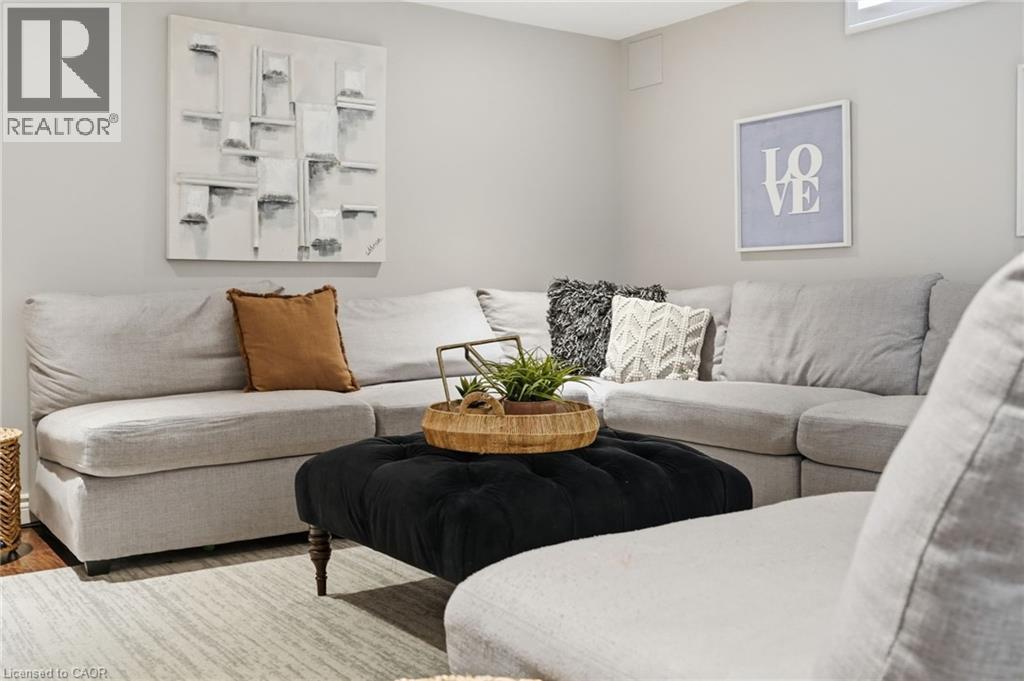 Spacious living area featuring light gray walls, a large sectional sofa, and a black tufted ottoman - 47 Winners Way, Binbrook, ON - Indoor Photo Showing Living Room