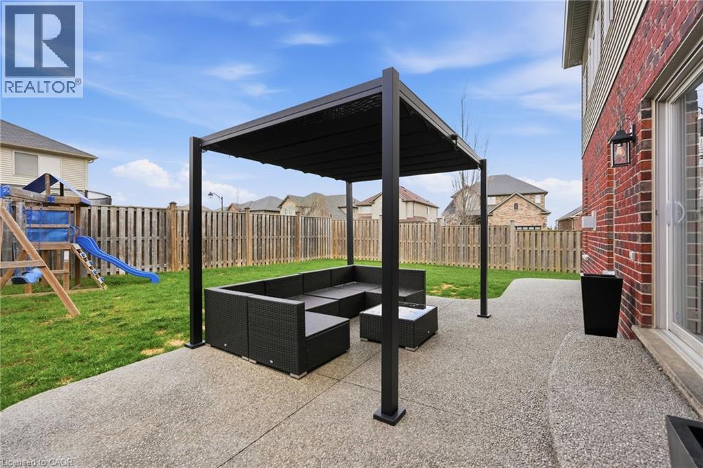 Expansive backyard featuring a large exposed aggregate patio, a dedicated pergola, and a privacy fence - 47 Winners Way, Binbrook, ON - Outdoor