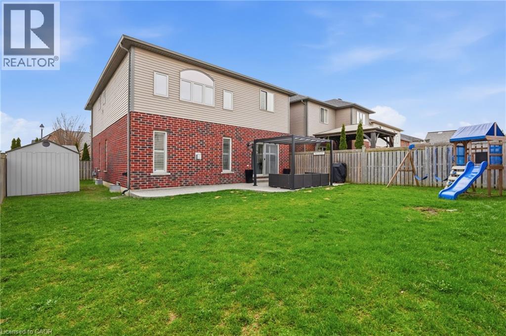 Expansive green lawn with a privacy fence, concrete patio, and garden shed - 47 Winners Way, Binbrook, ON - Outdoor With Exterior