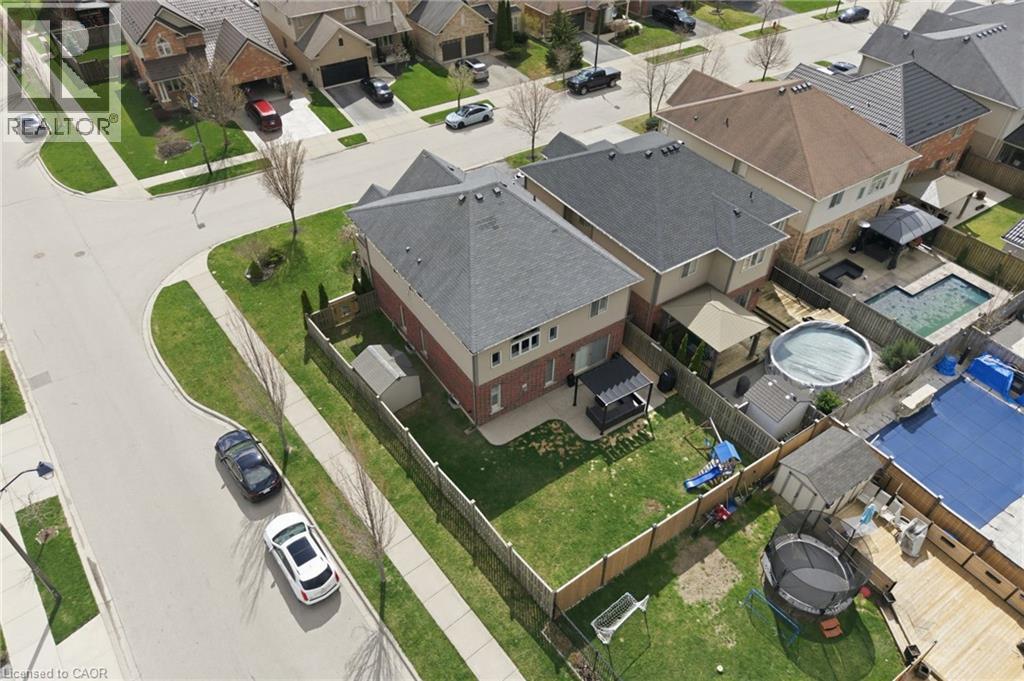 Rear yard featuring a green lawn, wood fence, and a patio area with a pergola - 47 Winners Way, Binbrook, ON - With View