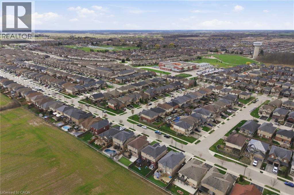 Aerial perspective showcasing a residential community with diverse single-family homes, manicured lawns, paved streets, and a green space in the distance - 47 Winners Way, Binbrook, ON - Outdoor With View
