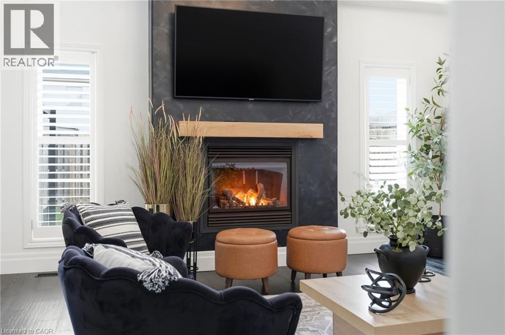 Modern living area featuring a dark-toned fireplace surround with a light wood mantel, a built-in gas fireplace, and dark wood-finish flooring - 47 Winners Way, Binbrook, ON - Indoor Photo Showing Living Room With Fireplace