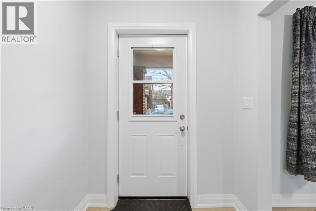White paneled entry door with clear glass inserts, light grey wall paint, white trim, and wood-finish flooring - 149 Lottridge Street, Hamilton, ON - Indoor Photo Showing Other Room