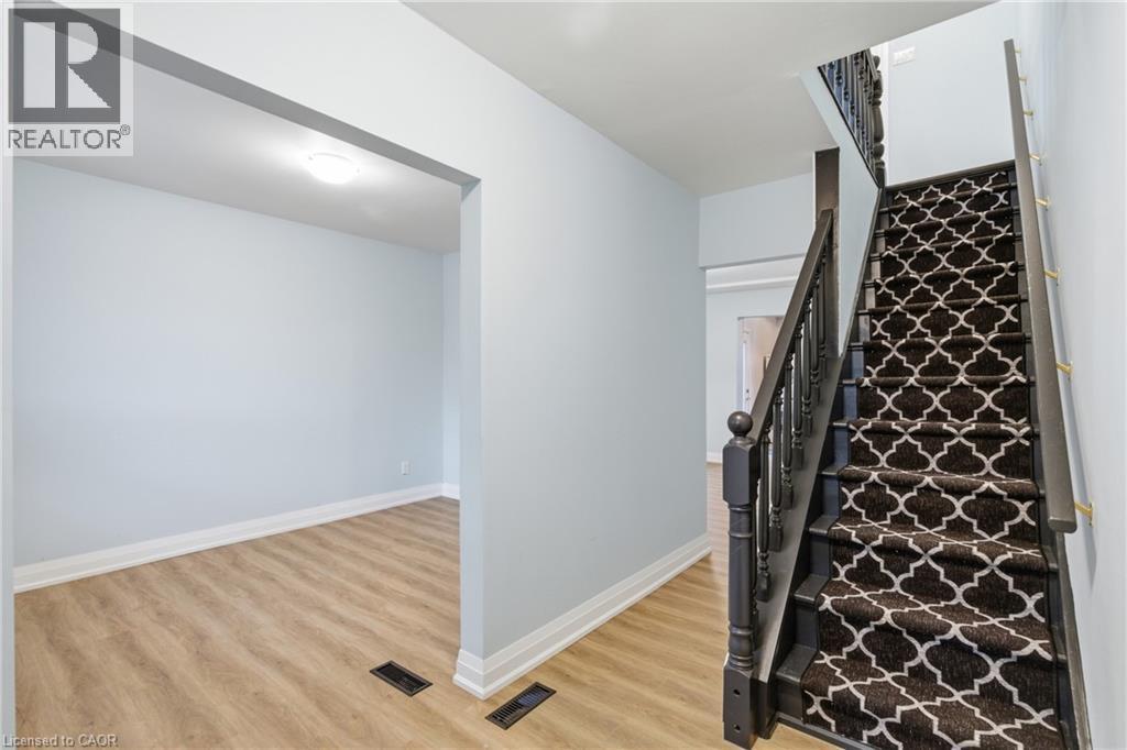 Staircase featuring dark wood newel posts and spindles, carpeted treads with a white and black geometric pattern, and a light wood-finish flooring - 149 Lottridge Street, Hamilton, ON - Indoor Photo Showing Other Room