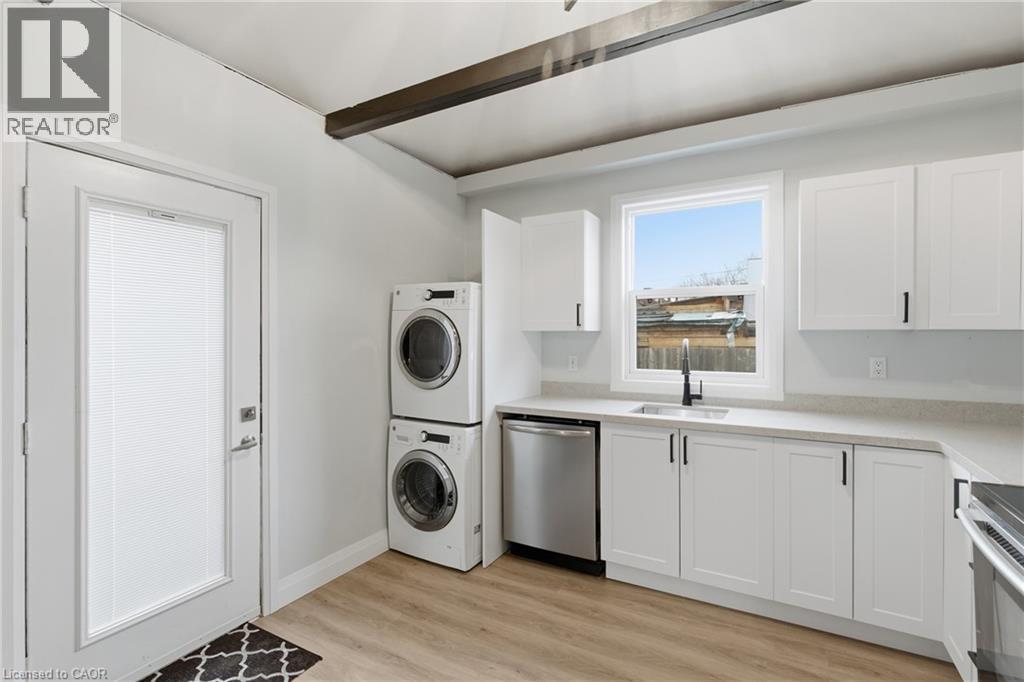 Contemporary kitchen featuring white cabinetry, light-toned countertops, and a stainless steel dishwasher - 149 Lottridge Street, Hamilton, ON - Indoor Photo Showing Laundry Room
