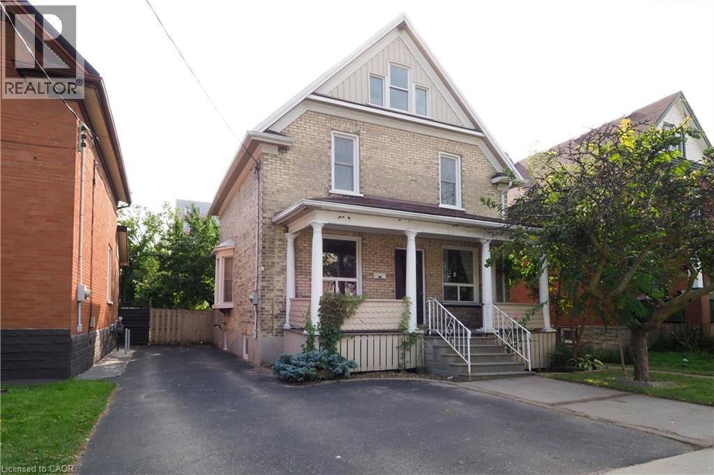 Two-story brick facade residence featuring a covered front porch with white columns and railing - 205 Duke Street E, Kitchener, ON - Outdoor With Deck Patio Veranda With Facade