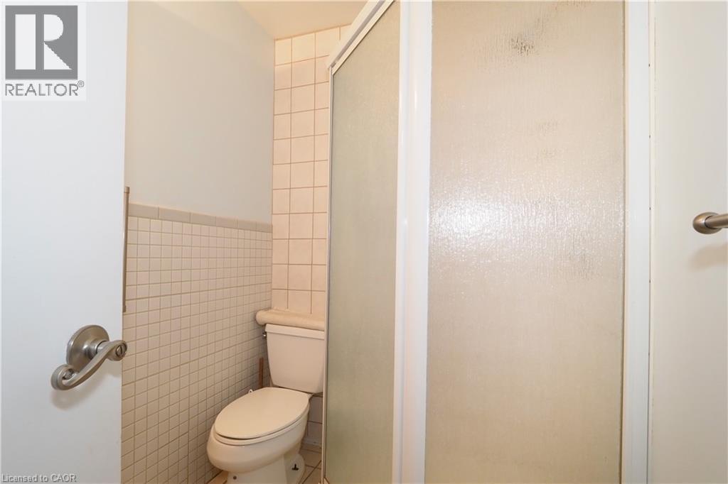 Bathroom featuring a commode, tiled walls, and an enclosed shower with a frosted glass door - 205 Duke Street E, Kitchener, ON - Indoor Photo Showing Bathroom