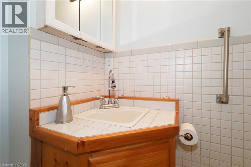 Corner vanity with wood cabinetry, tile countertop, and integrated sink - 205 Duke Street E, Kitchener, ON - Indoor Photo Showing Bathroom