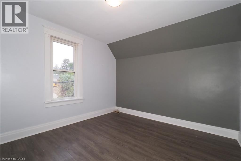 Room featuring wood-finish flooring, white baseboards, and a single window with white trim - 205 Duke Street E, Kitchener, ON - Indoor Photo Showing Other Room
