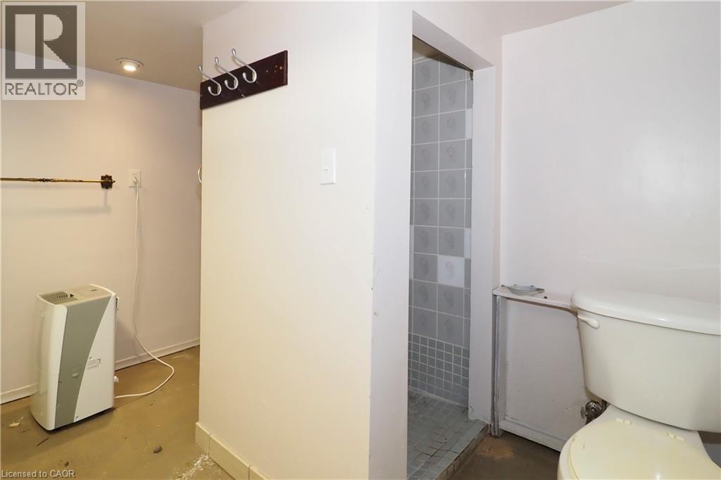 Bathroom area featuring a tiled shower stall and white toilet - 205 Duke Street E, Kitchener, ON - Indoor Photo Showing Bathroom