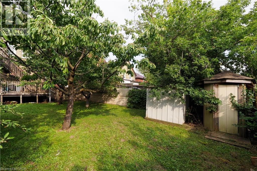 Expansive grassy yard featuring mature trees, a multi-level wood deck, a wood-paneled shed, and a hexagonal gazebo - 205 Duke Street E, Kitchener, ON - Outdoor