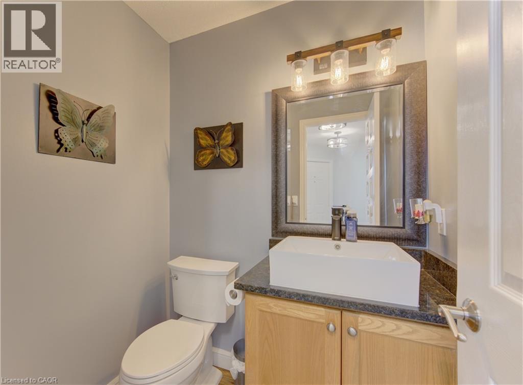 Powder room featuring a vessel sink, dark countertop, and wood-finish cabinetry - 512 Hidden Creek Drive, Kitchener, ON - Indoor Photo Showing Bathroom