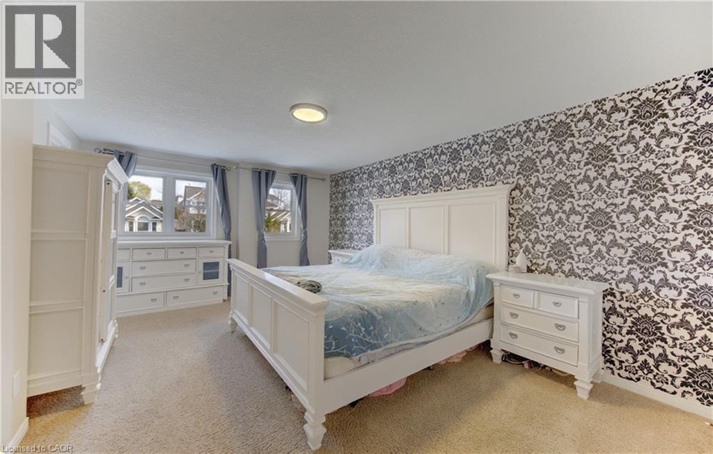 Bedroom featuring a patterned accent wall, carpet flooring, and multiple windows - 512 Hidden Creek Drive, Kitchener, ON - Indoor Photo Showing Bedroom