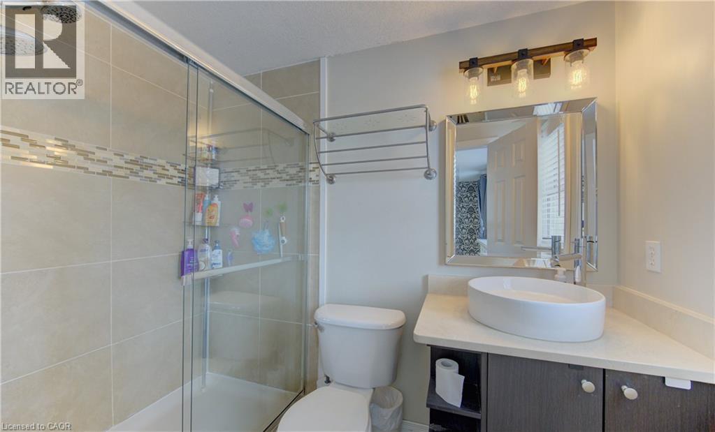 Bathroom featuring a glass-enclosed shower with tile surround and decorative mosaic accent band - 512 Hidden Creek Drive, Kitchener, ON - Indoor Photo Showing Bathroom