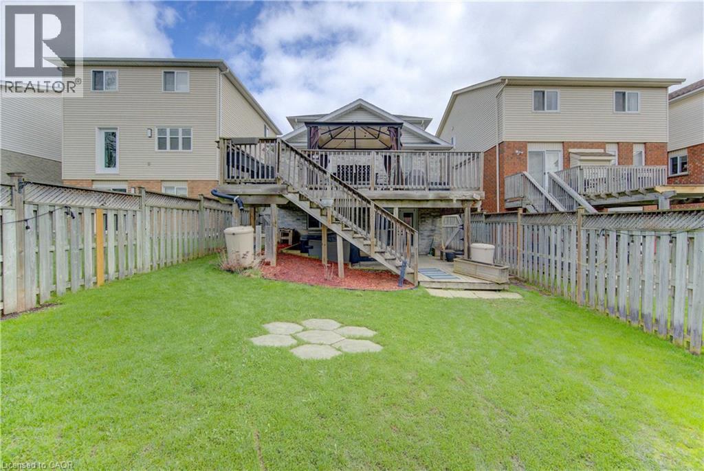 Expansive backyard featuring a manicured lawn, full fencing, and a decorative stone paver pattern - 512 Hidden Creek Drive, Kitchener, ON - Outdoor With Deck Patio Veranda With Exterior