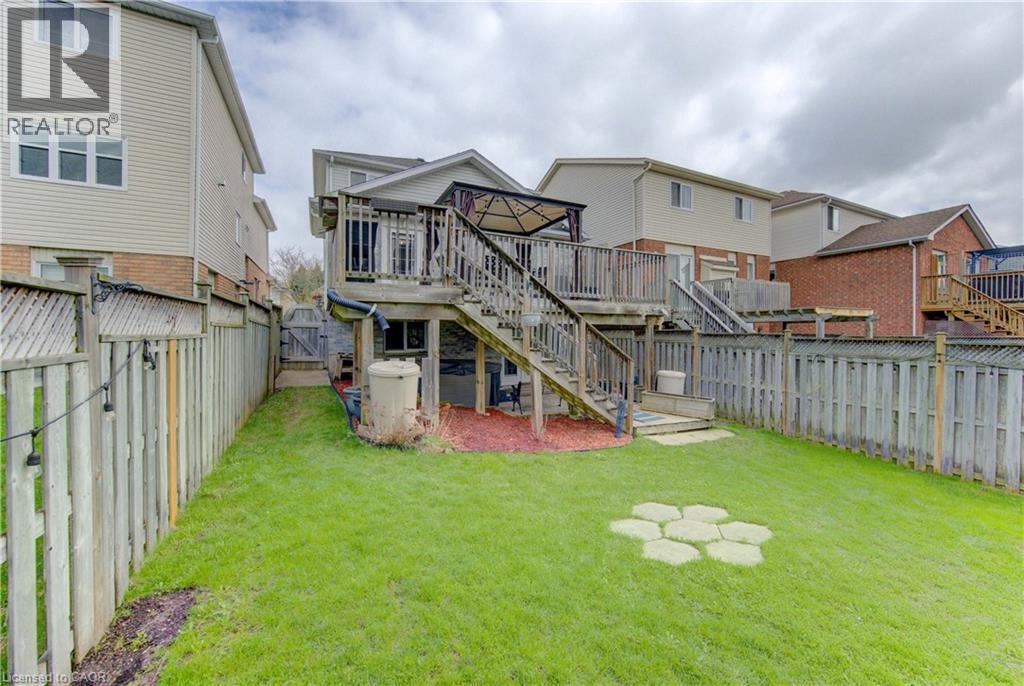Rear exterior with wood deck and staircase, fenced perimeter, and green lawn space - 512 Hidden Creek Drive, Kitchener, ON - Outdoor With Deck Patio Veranda