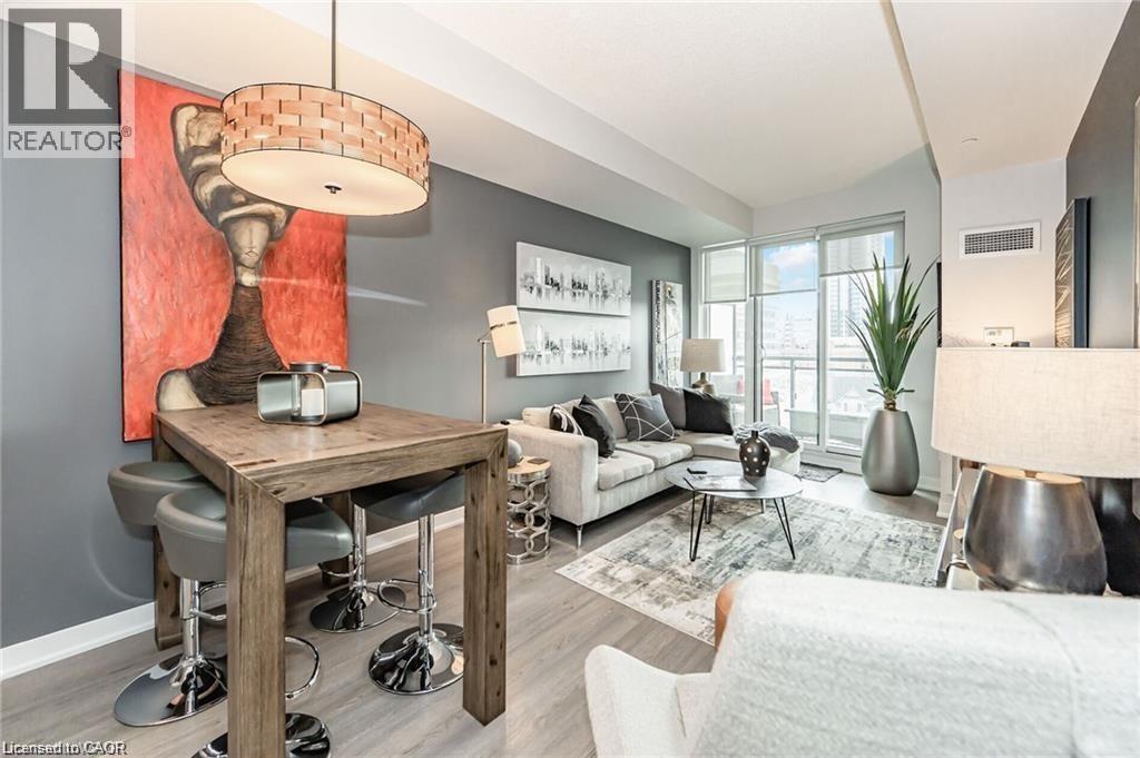 Open-concept living space featuring wood-finish flooring, a contemporary ceiling light fixture, floor-to-ceiling windows, and a glass-paneled balcony - 85 Duke Street W Unit# 507, Kitchener, ON - Indoor Photo Showing Living Room