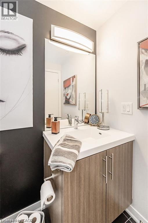 Contemporary vanity featuring a wood-look finish, white countertop, integrated sink, and brushed nickel hardware - 85 Duke Street W Unit# 507, Kitchener, ON - Indoor Photo Showing Bathroom