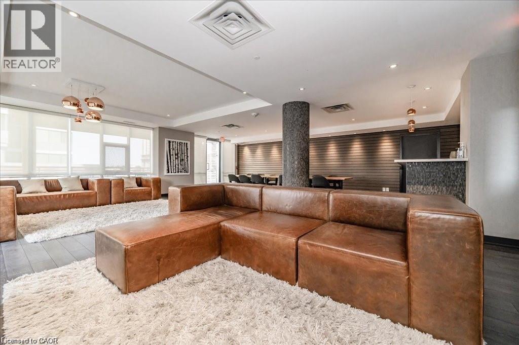 Spacious common area featuring dark wood-finish flooring, recessed lighting, and a textured accent wall - 85 Duke Street W Unit# 507, Kitchener, ON - Indoor Photo Showing Living Room