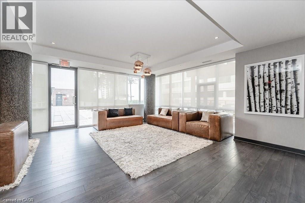 Spacious common area featuring dark wood-finish flooring, a full wall of windows with roller shades, and recessed lighting - 85 Duke Street W Unit# 507, Kitchener, ON - Indoor Photo Showing Other Room